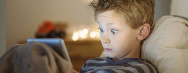 5 Vantaggi dei videogiochi titolo Videogiochi: Bambino fissa lo schermo di un pad