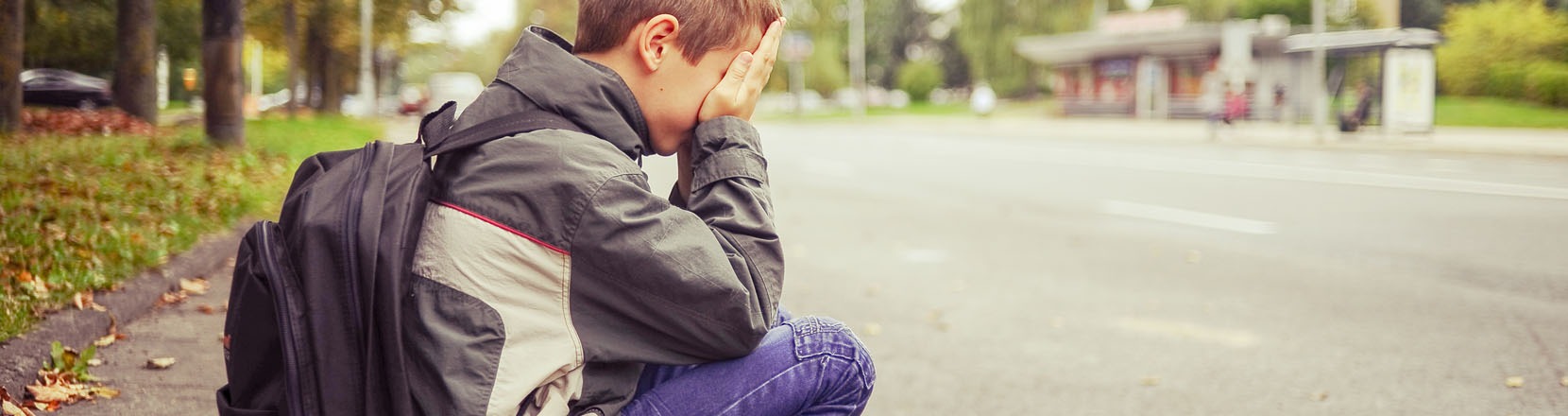 Ragazzino triste piange seduto sul marciapiede, scarsa autostima