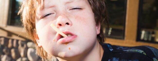 Bambini e ragazzi difficili Bambini e ragazzi difficili: Bambino che tiene in bocca una patatina come se fosse una sigaretta