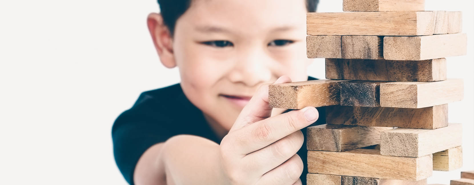 Bambino che sfila un mattoncino di legno da una torre