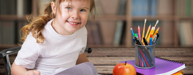 Si distrae durante i compiti, bambina che sorride mentre fa i compiti
