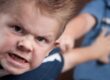Mio figlio morde e picchia, bambino con espressione aggressiva che spinge via il fratello