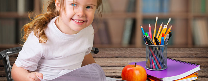 Bambina pronta a scrivere con quaderno e penne