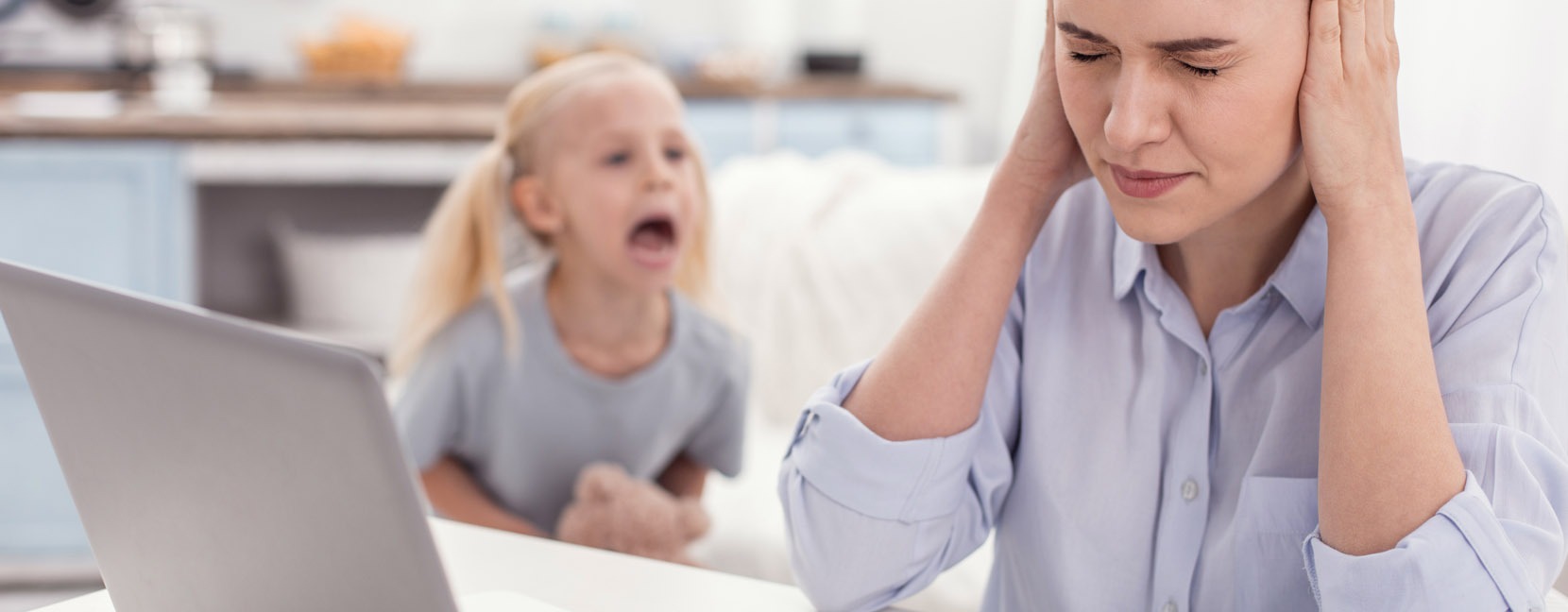 Bambina che urla arrabbiata e mamma che reagisce tappandosi le orecchie e chiudendo gli occhi