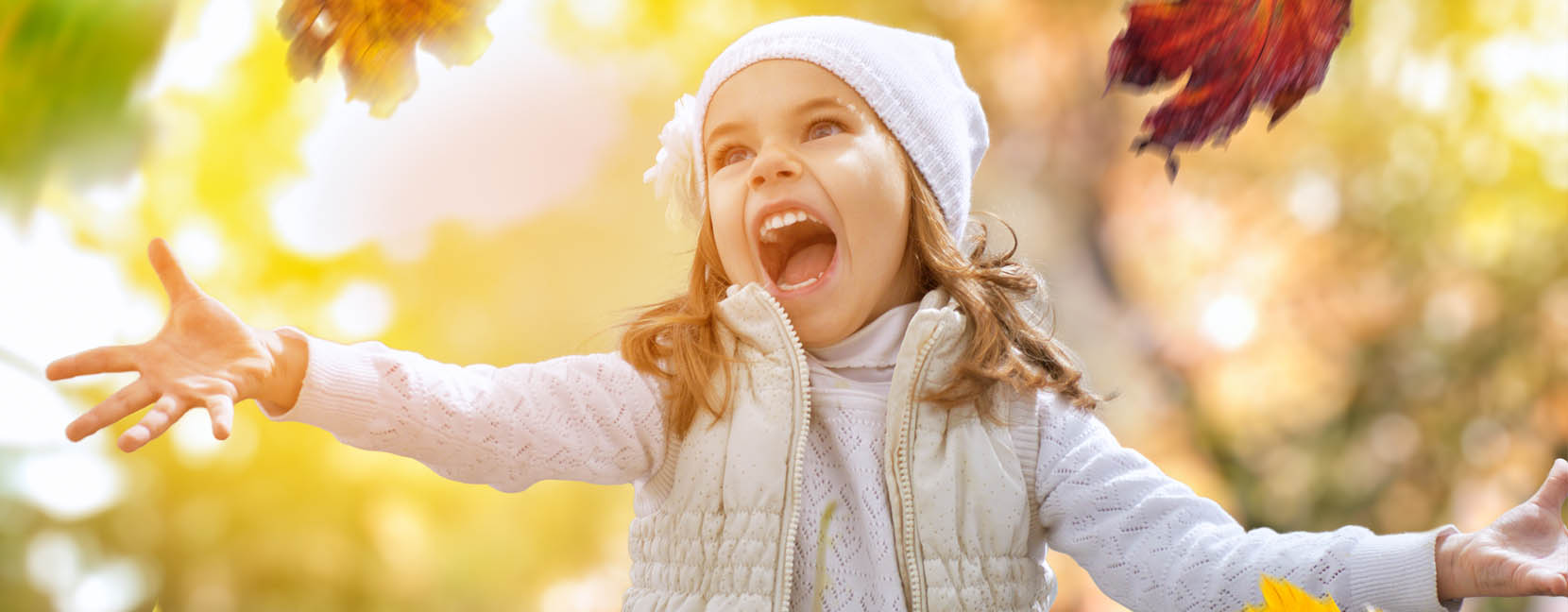 Bambina che lancia urlando delle foglie contenta