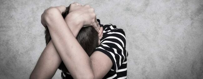 Titolo-smettila-di-picchiare-tuo-figlio bambino si copre la testa e ha paura di essere picchiato