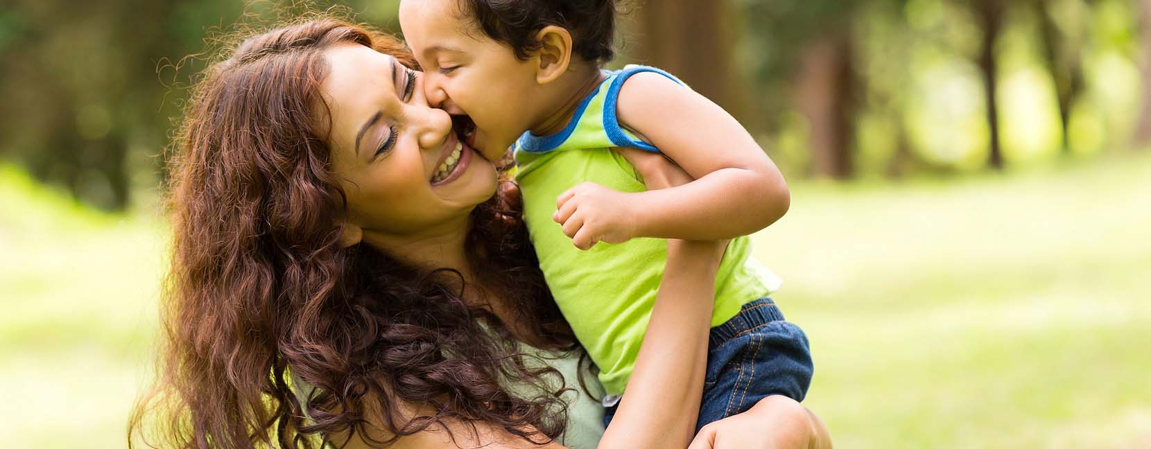 Mamma felice che tiene il suo bimbo sorridente in braccio.