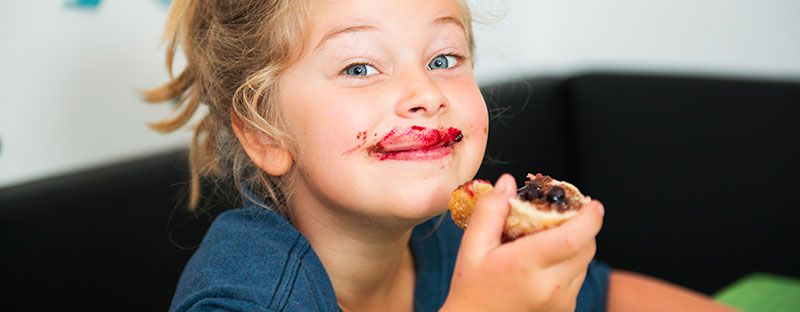 Bambina soddisfatta e felice mangia pane e marmellata