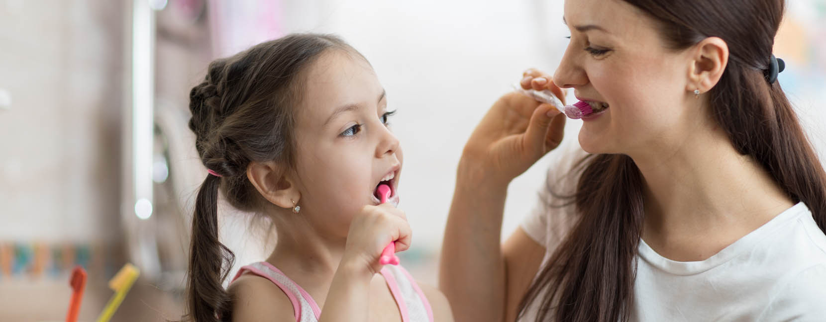 Mamma e figlia si lavano i denti insieme con viso sorridente