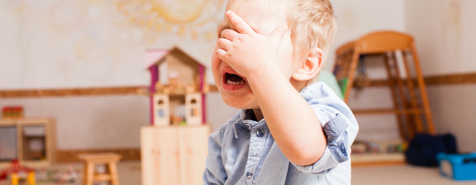 Bambino piccolo che piange tenendo la mano sugli occhi