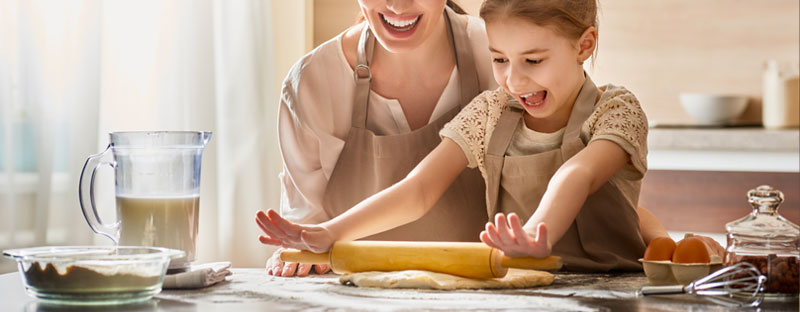 bambina felice che ha davanti gli ingredienti per fare una torta