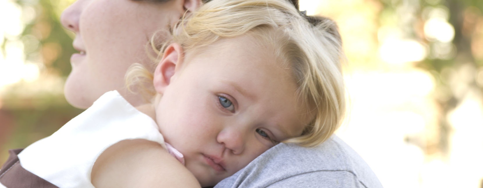 Bambina piccola che si appoggia triste sulla spalla della mamma