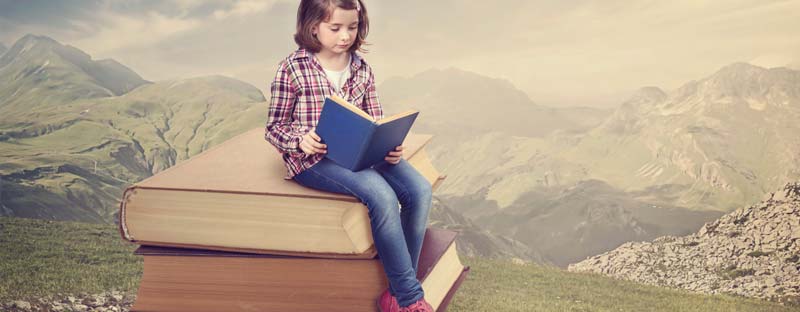 Bambina seduta su libri, legge un libro pieno di informazioni